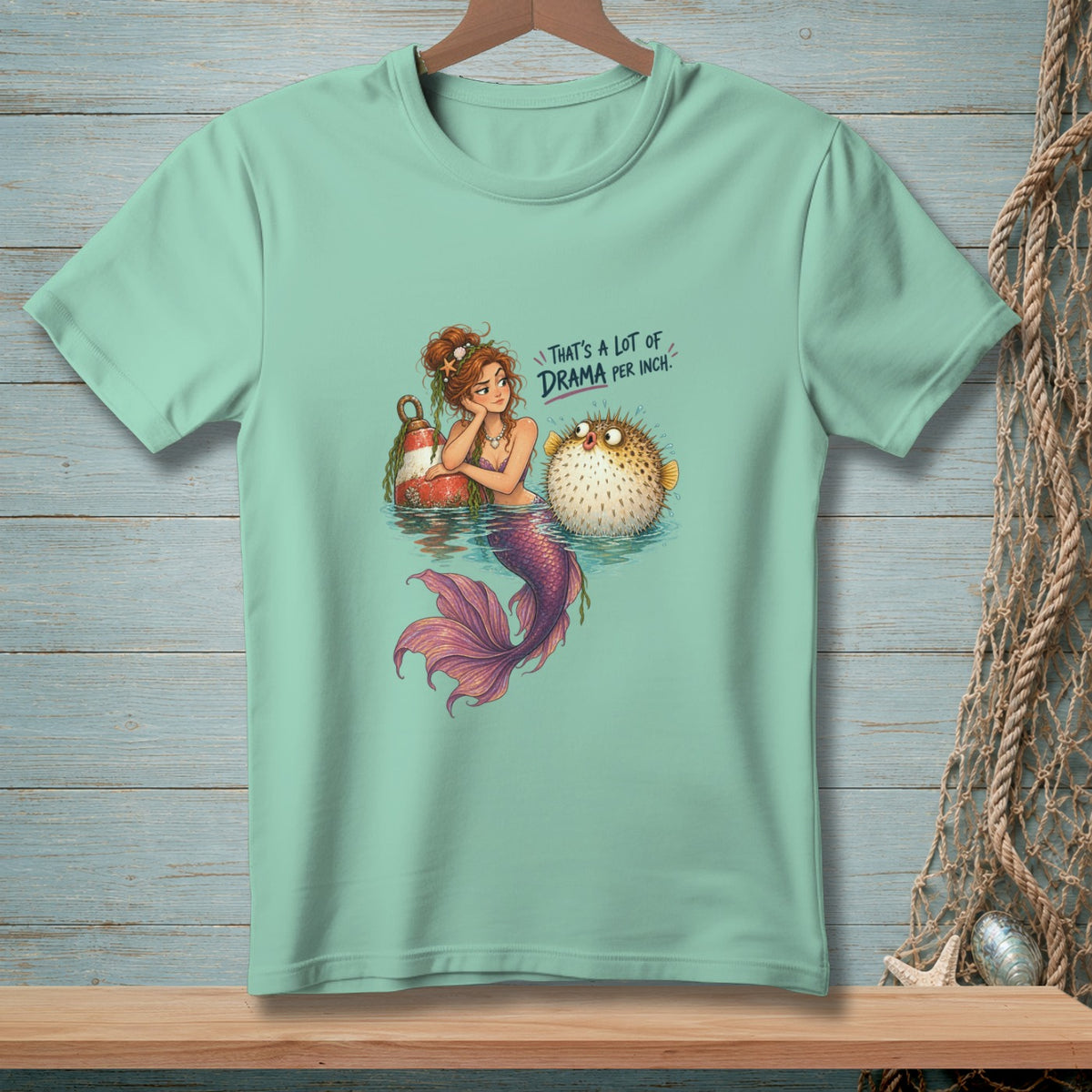 Mermaid with pufferfish and buoy, text reads "That's a lot of drama per inch."