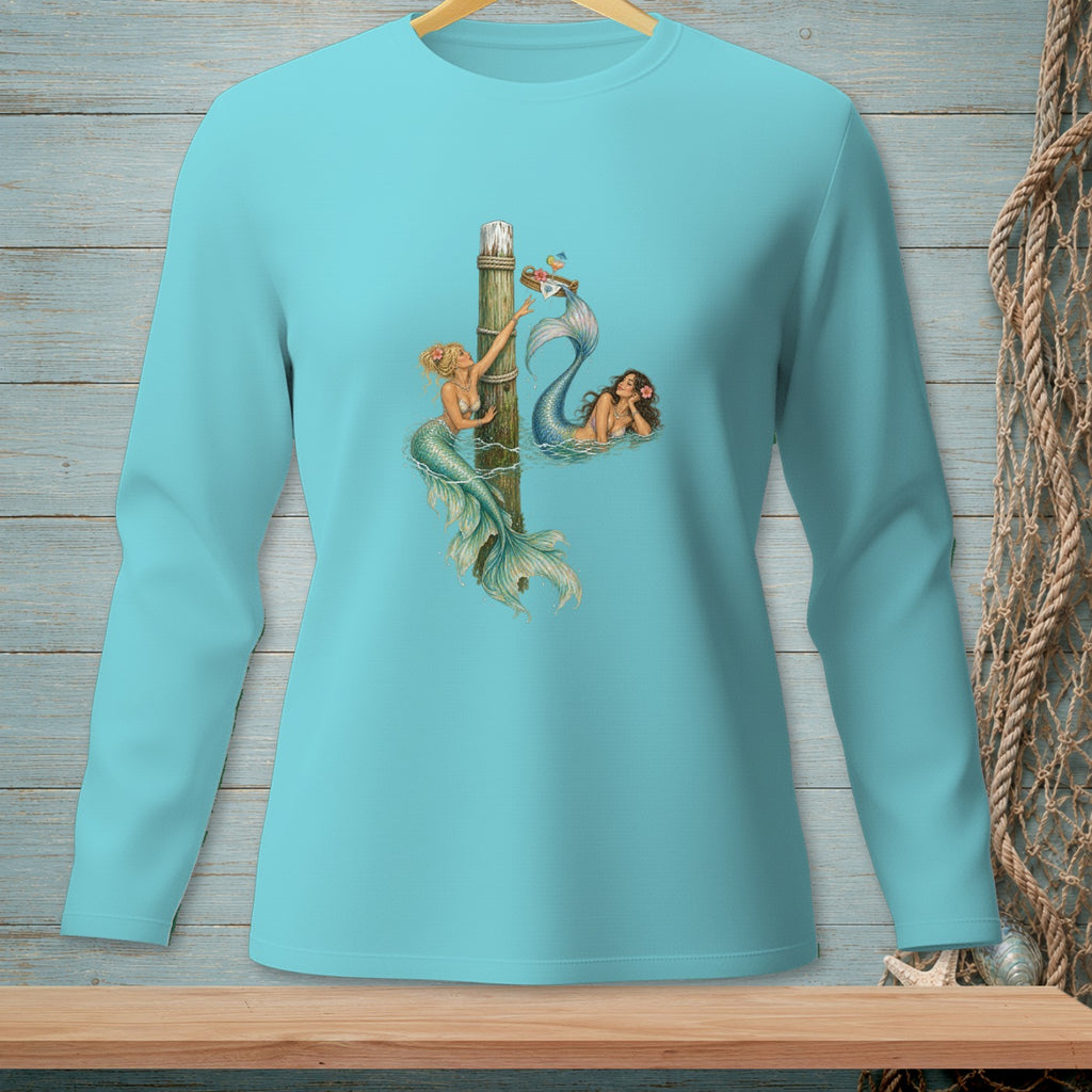 Two mermaids by a wooden post, one reaching for a basket of drinks.