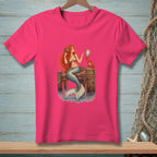 Pink t-shirt with a mermaid holding a mirror next to a crab on a wooden pier.