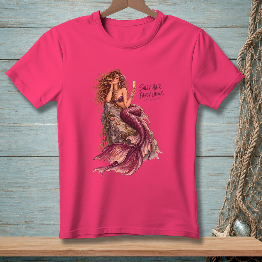 Pink t-shirt with a mermaid on a rock holding a drink, with text.