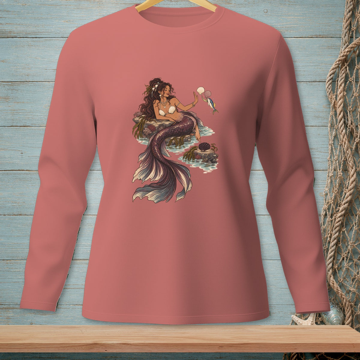 Mermaid sitting on rocks with shells and a fish.
