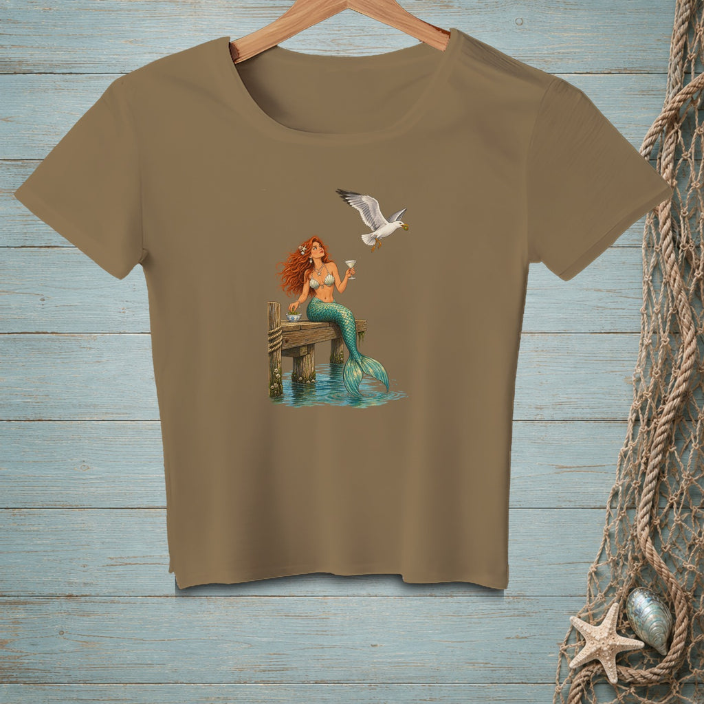 Brown t-shirt with mermaid on pier holding drink, seagull flying overhead.