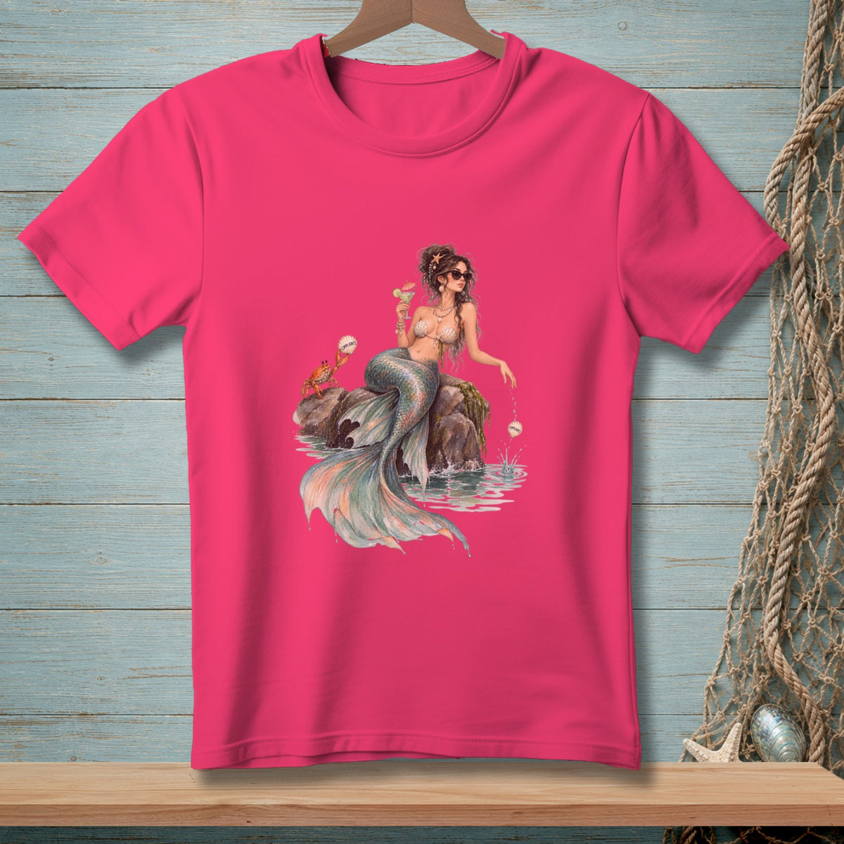 T-shirt with a mermaid, crab, and cocktail on rocks in the water.