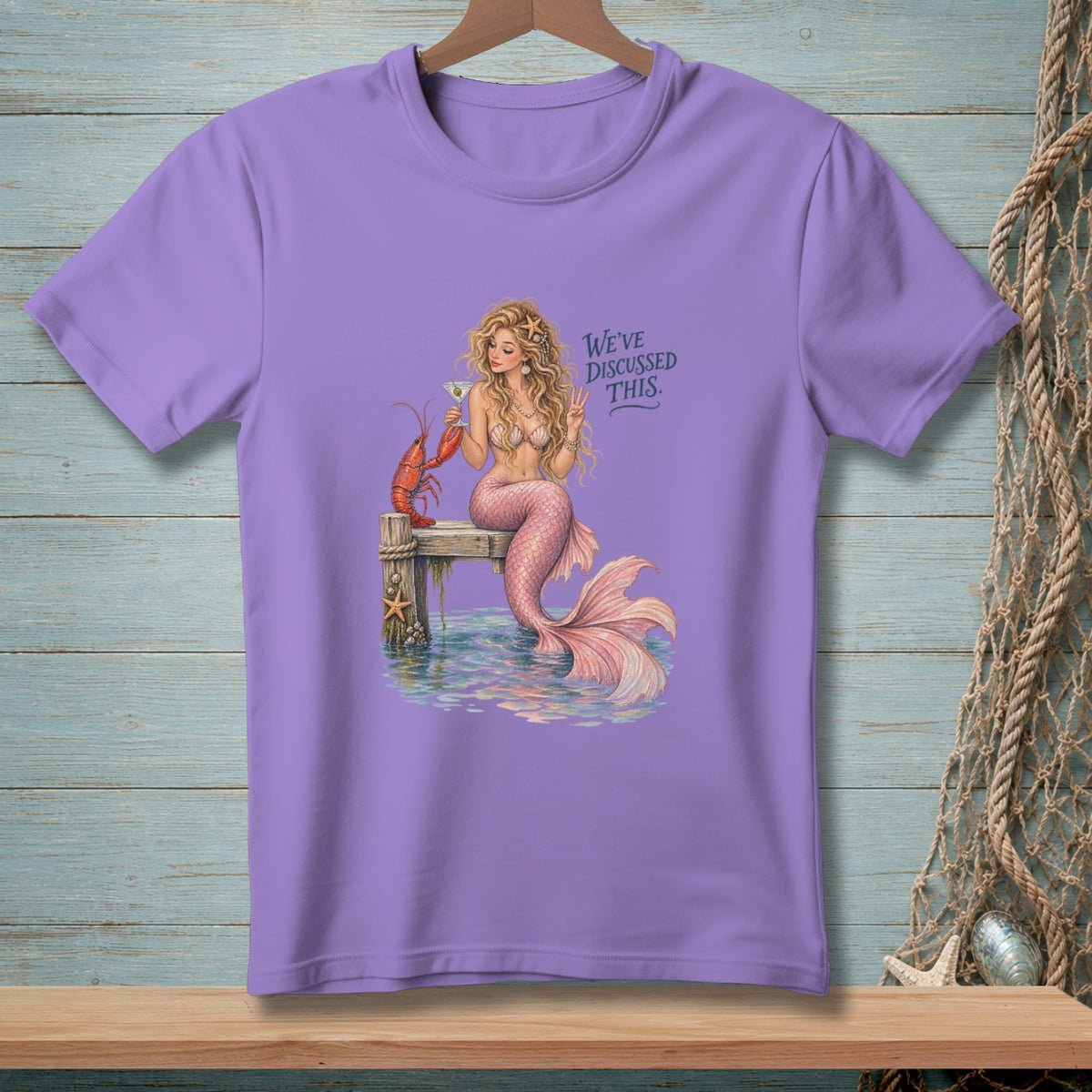 Mermaid with lobster on pier, holding drink, with text "We've Discussed This."