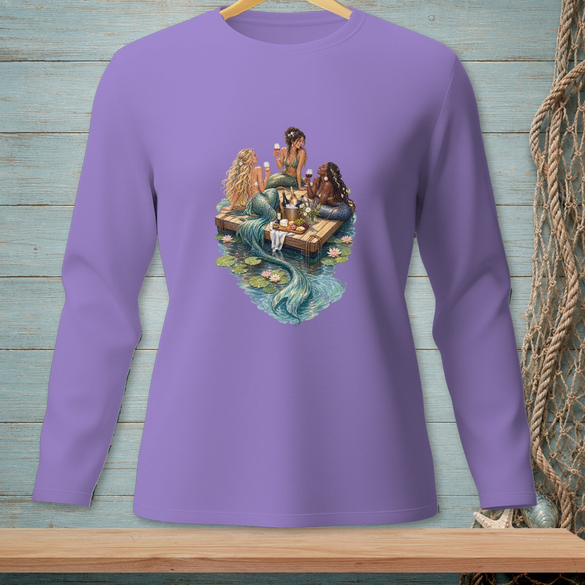 Three mermaids with tails sit on a wooden raft with wine and snacks, surrounded by water lilies.