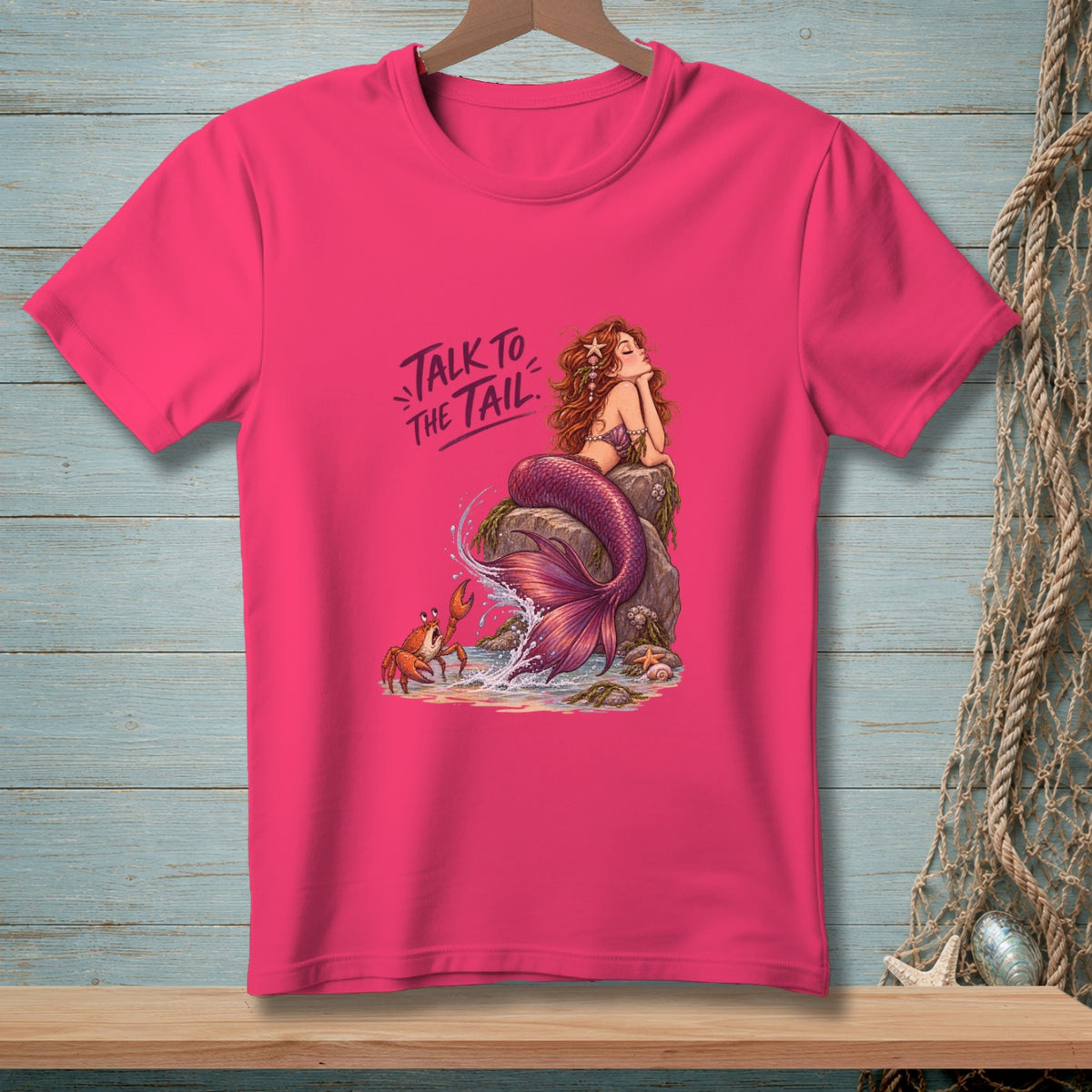 Pink t-shirt with illustration of a mermaid, crab, and text "Talk to the Tail".