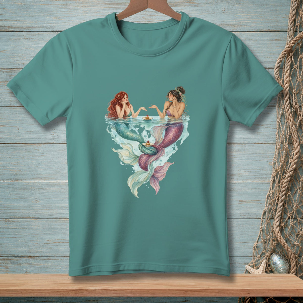 Two mermaids with colorful tails share cupcakes in the water.