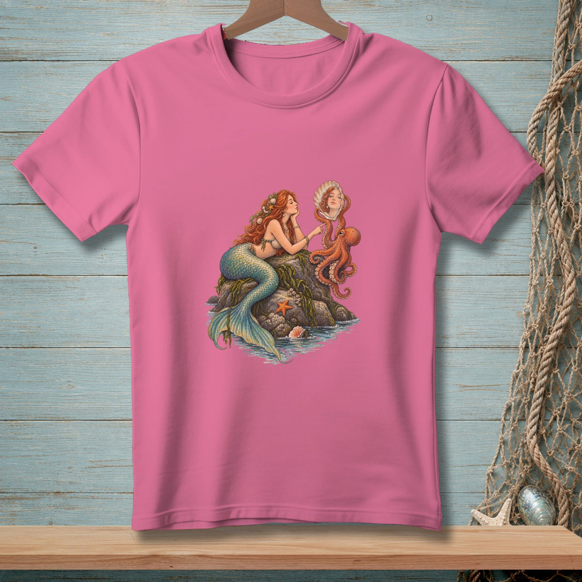 Pink t-shirt with mermaid and octopus artwork showing a mermaid looking in a seashell mirror.