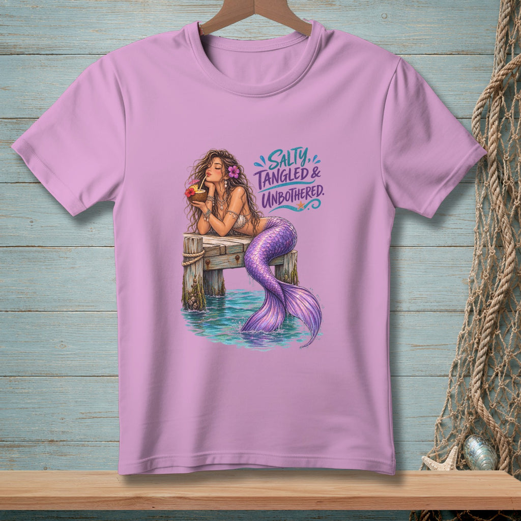 Pink t-shirt with a mermaid drinking from a coconut on a dock. Text says "Salty, Tangled & Unbothered."