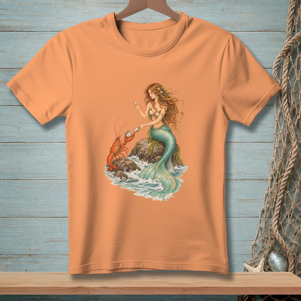 Peach t-shirt with mermaid holding pearl and lobster on rocks with waves.