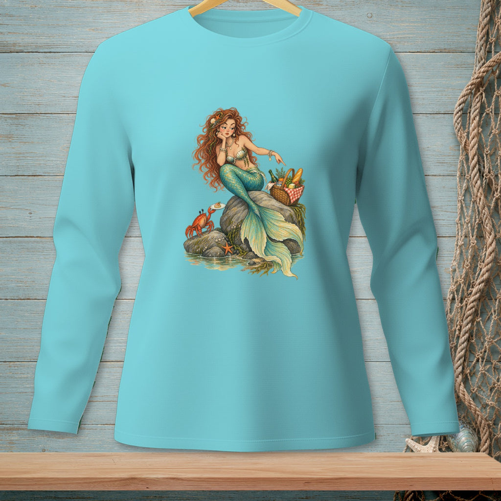 Turquoise long-sleeve shirt with a graphic of a mermaid sitting on a rock next to a picnic basket and a crab.