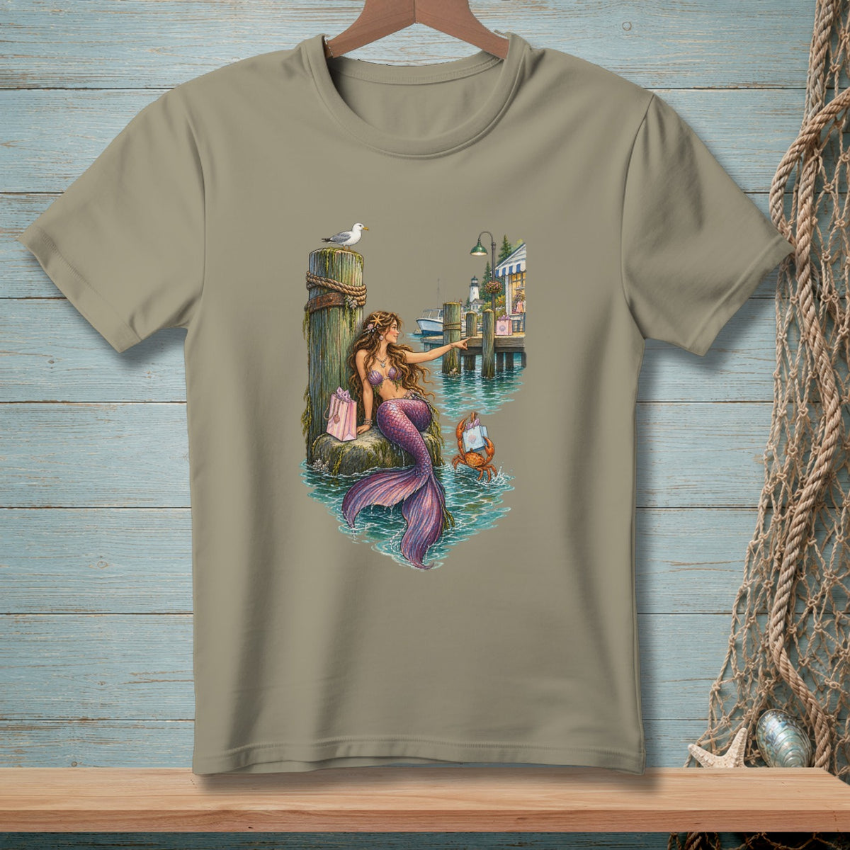 Mermaid with purple tail sitting by pier with seagull, crab, and village buildings.