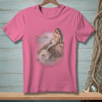 Pink t-shirt with an artistic print of a mermaid sitting on a rock by the sea.