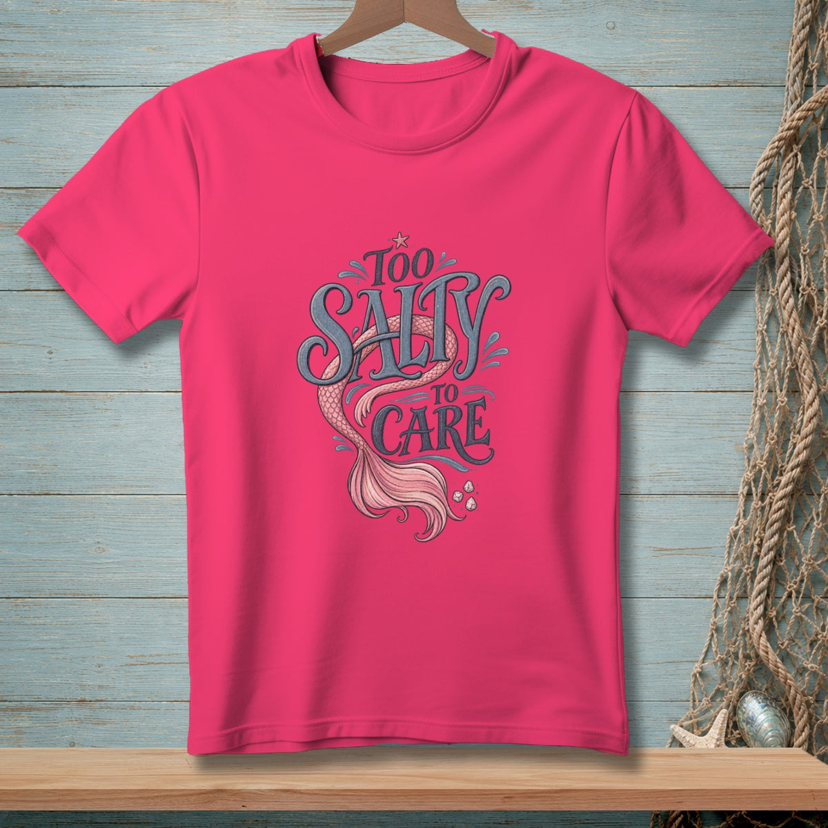 Pink t-shirt with "Too Salty To Care" text and mermaid tail graphic.