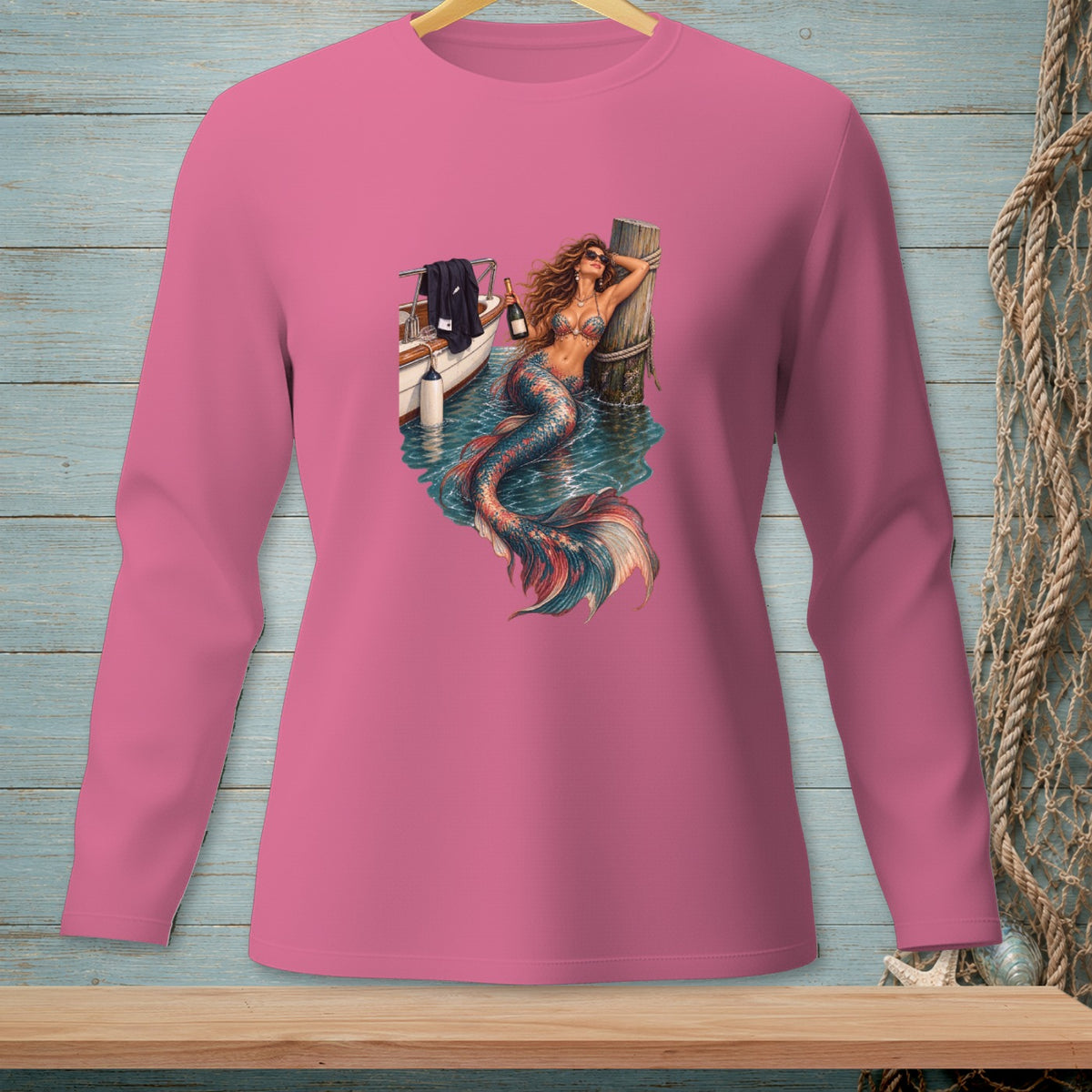 Pink long-sleeve shirt with a mermaid graphic holding a bottle by a boat.