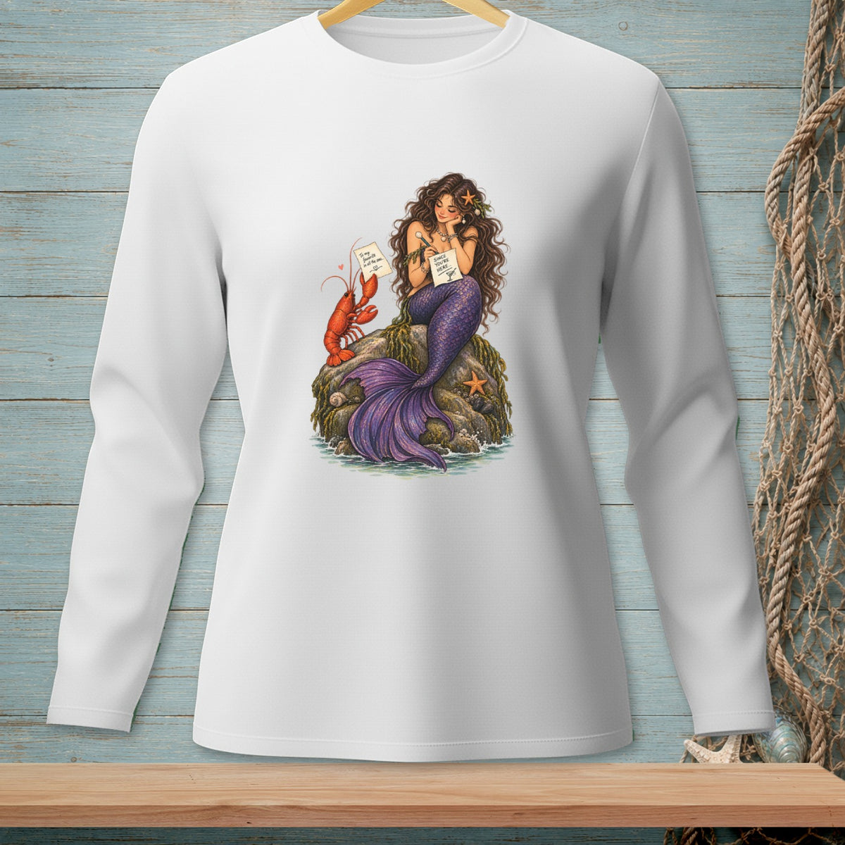 Mermaid holding notes with lobster on rock, wearing a white long-sleeve shirt.