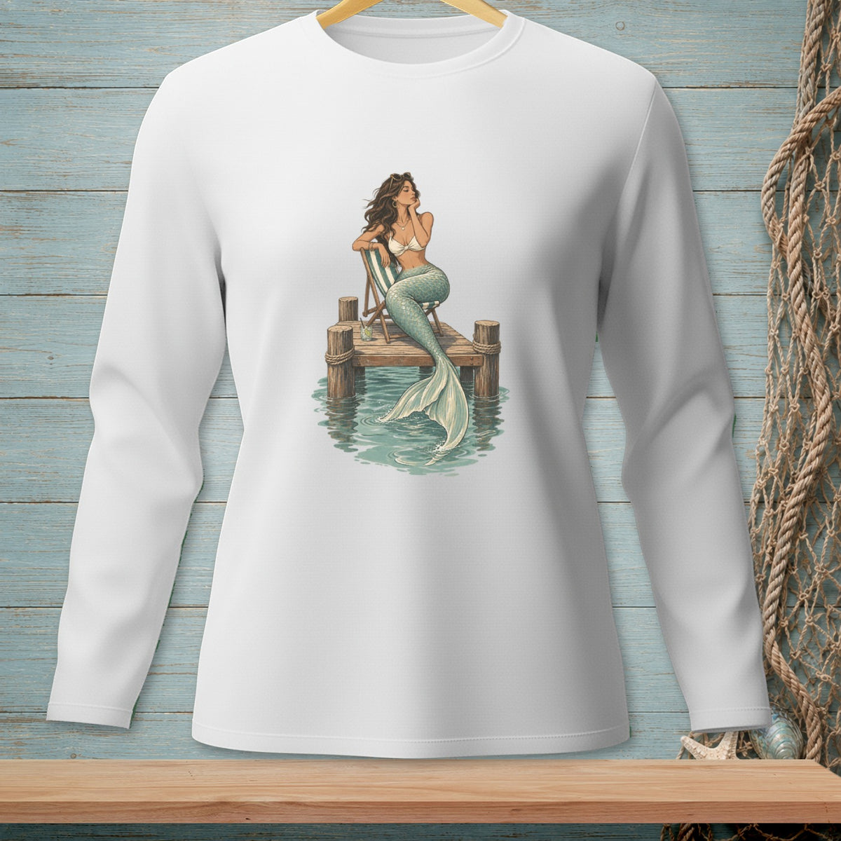 White long-sleeve shirt with a mermaid sitting on a dock illustration.