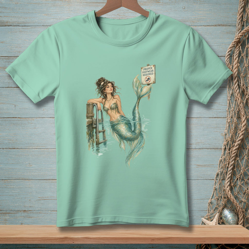 Mermaid leaning on dock near "Proper Footwear Required" sign.