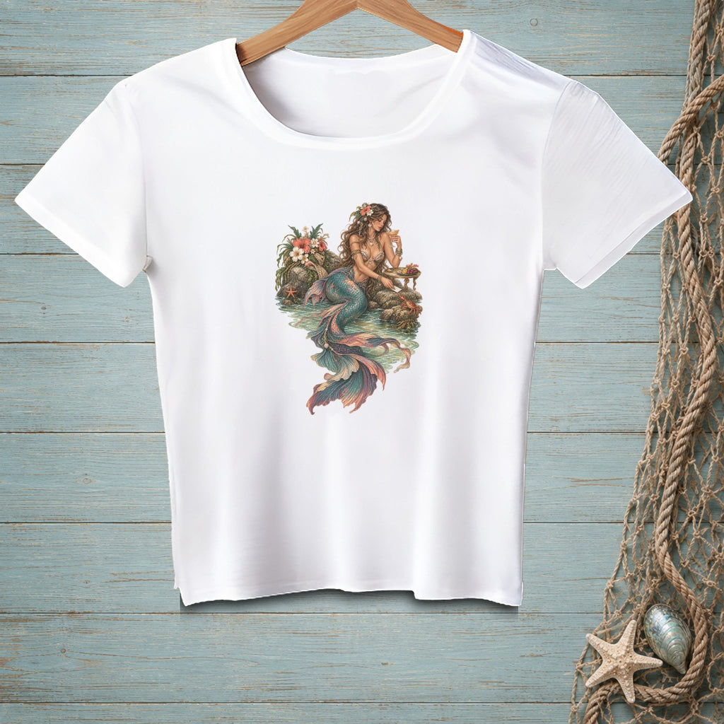 White t-shirt with vintage-style mermaid illustration on a rocky shore.