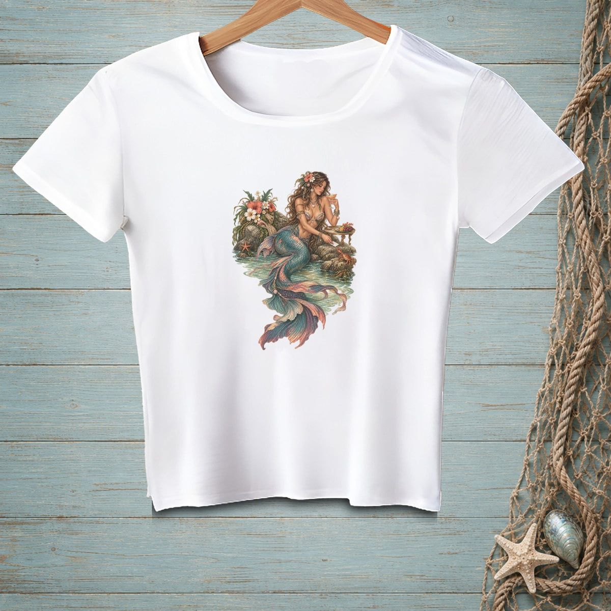 White t-shirt with vintage-style mermaid illustration on a rocky shore.