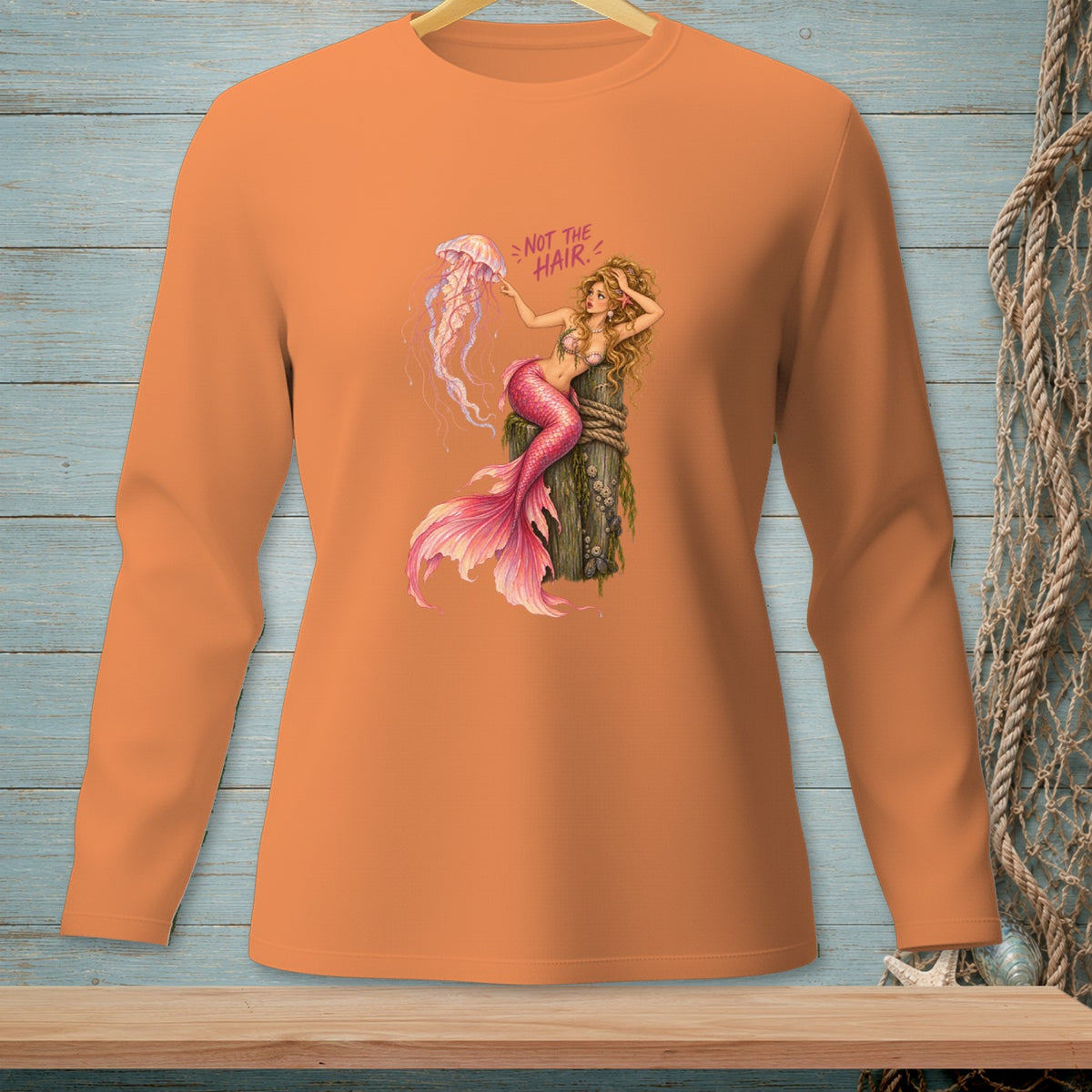 Mermaid with pink tail holds jellyfish and text "NOT THE HAIR" on orange shirt.