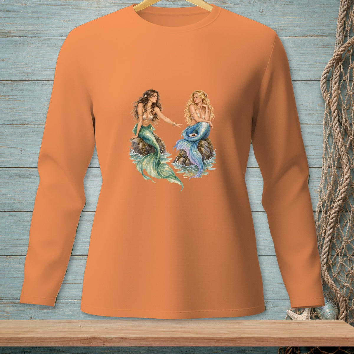 Orange long-sleeved shirt with two mermaids sitting on rocks.