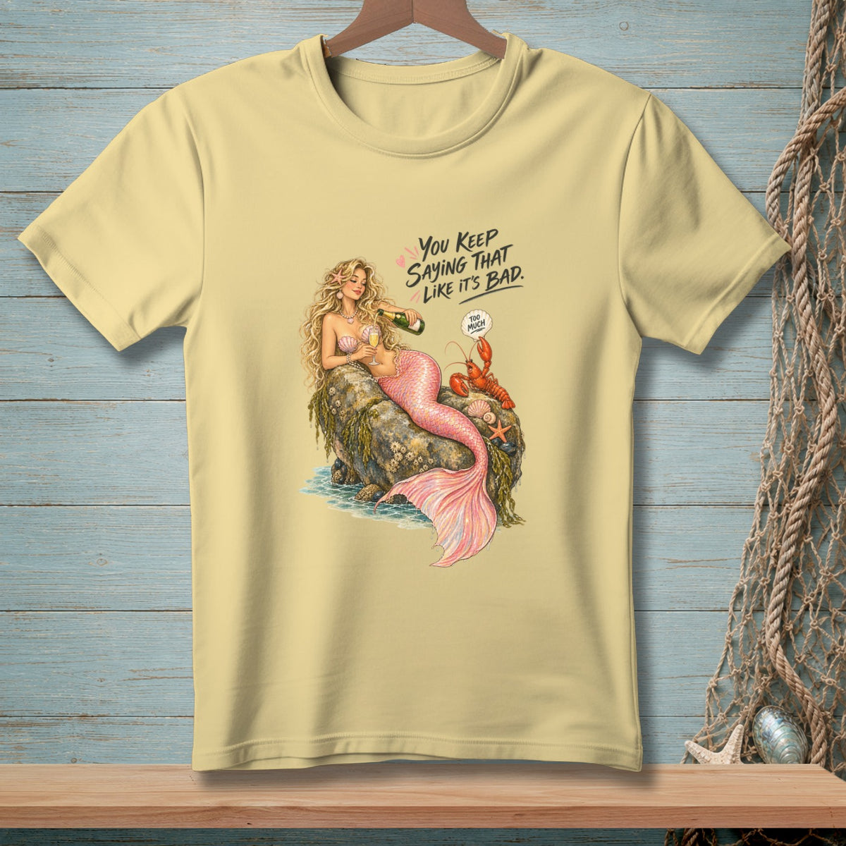 Yellow t-shirt with mermaid pouring champagne, text "You keep saying that like it's bad".