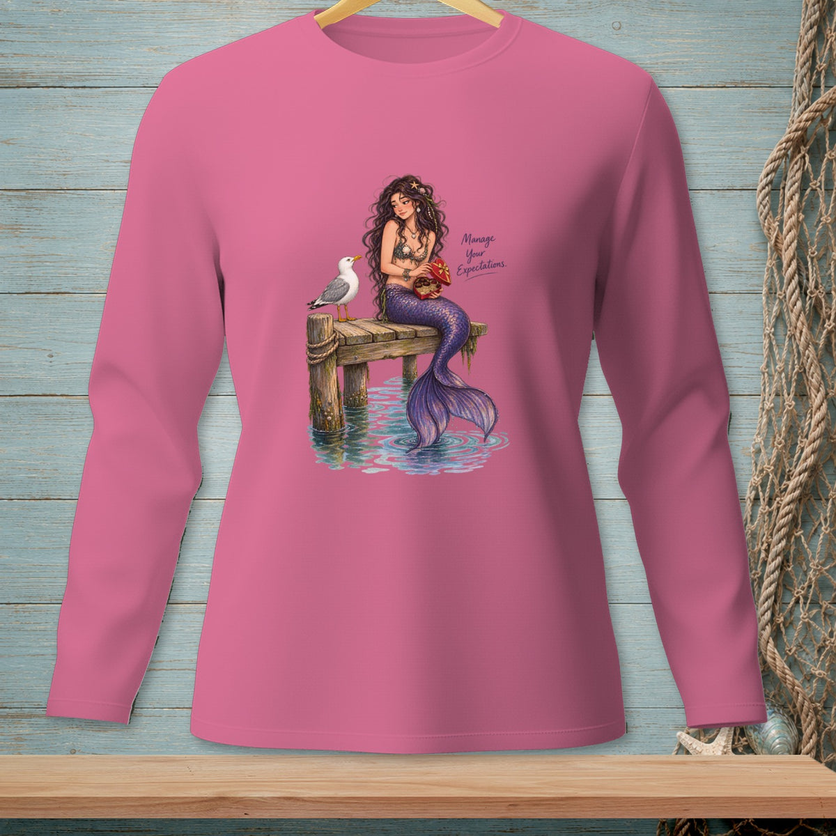 Pink long-sleeved shirt with mermaid illustration and text "Manage Your Expectations".