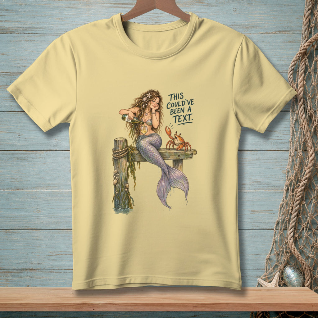 Light yellow t-shirt with a mermaid pouring champagne next to a crab, with text.
