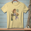 Light yellow t-shirt with a mermaid pouring champagne next to a crab, with text.