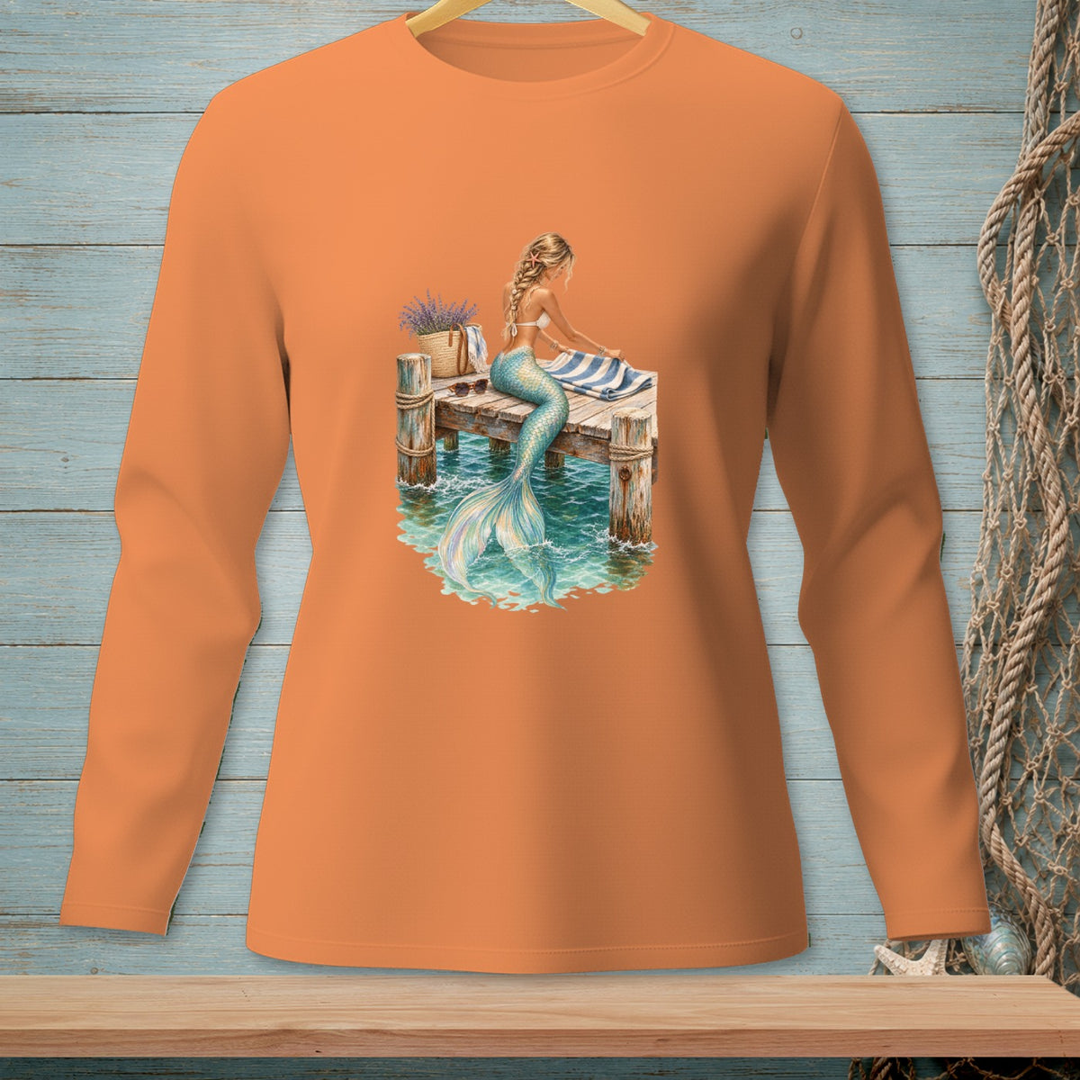 Orange long-sleeve shirt with a graphic of a mermaid on a dock.