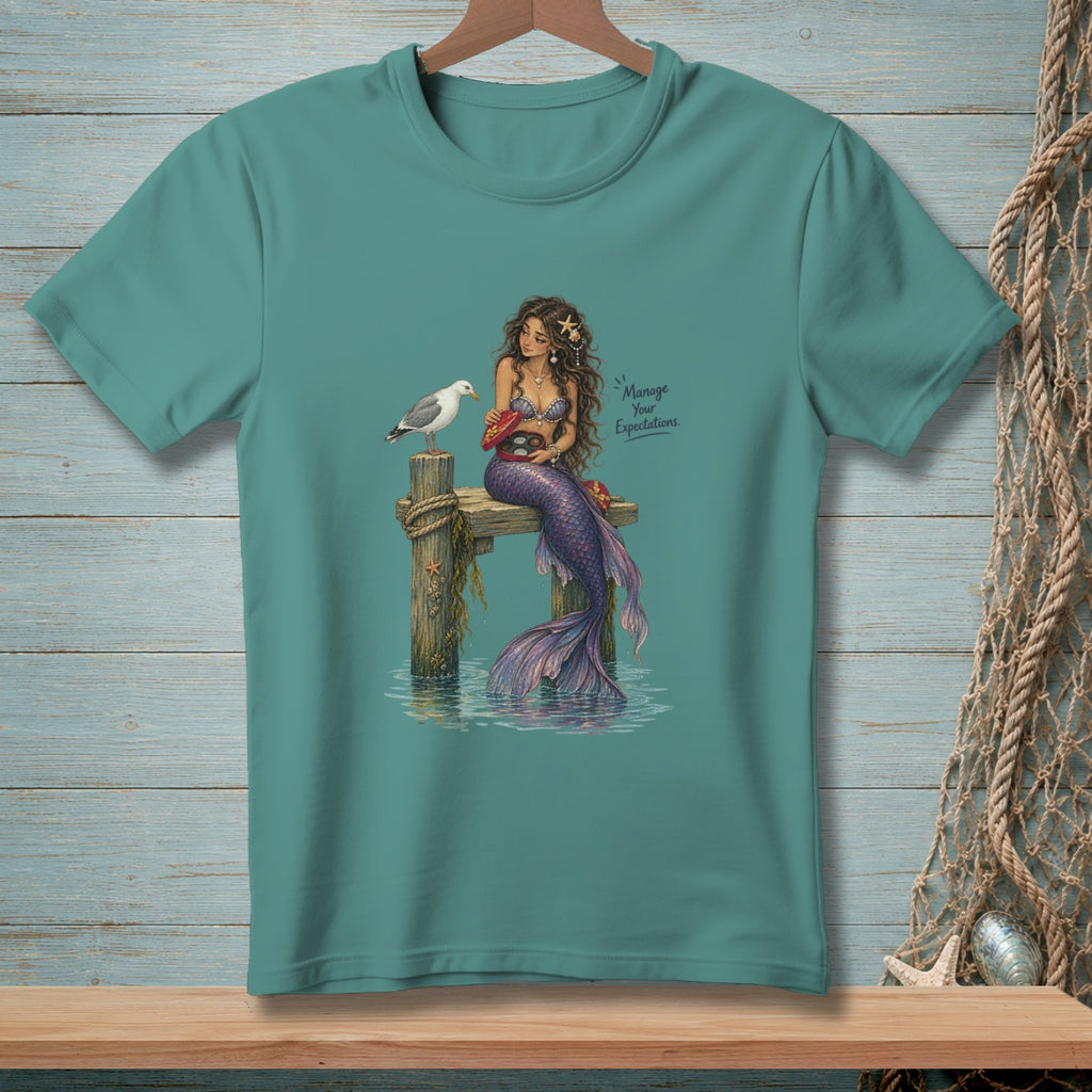 Mermaid with purple tail sits on a dock offering food to a seagull.