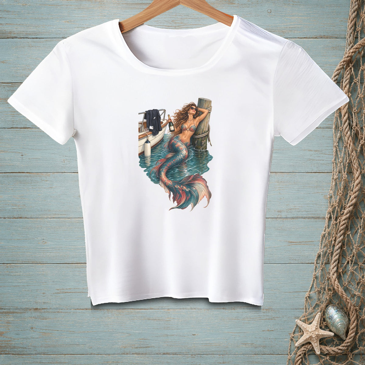 White t-shirt with a graphic of a mermaid leaning on a pole by a boat.