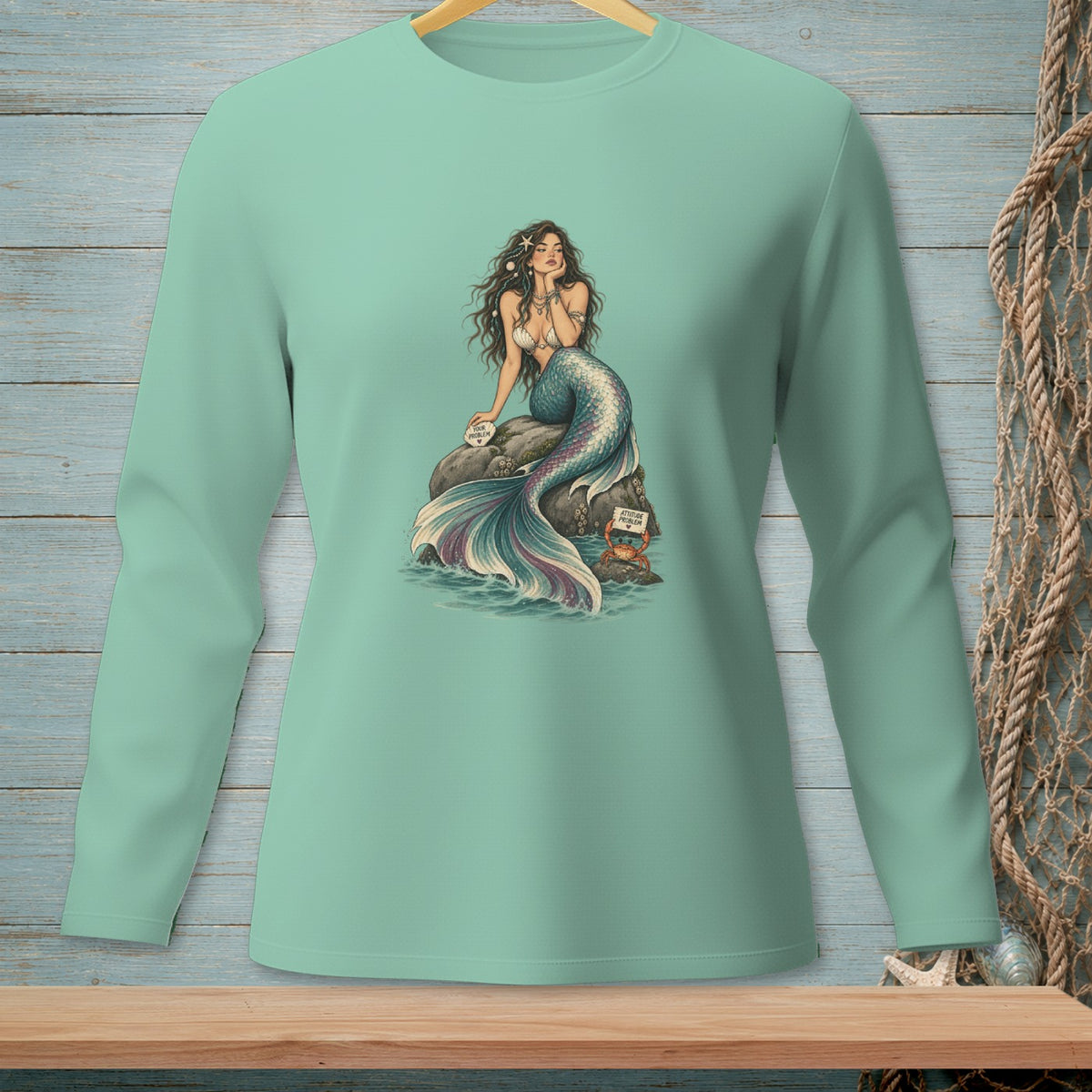 Mint long sleeve shirt with a seated mermaid, a rock, and a crab with text.