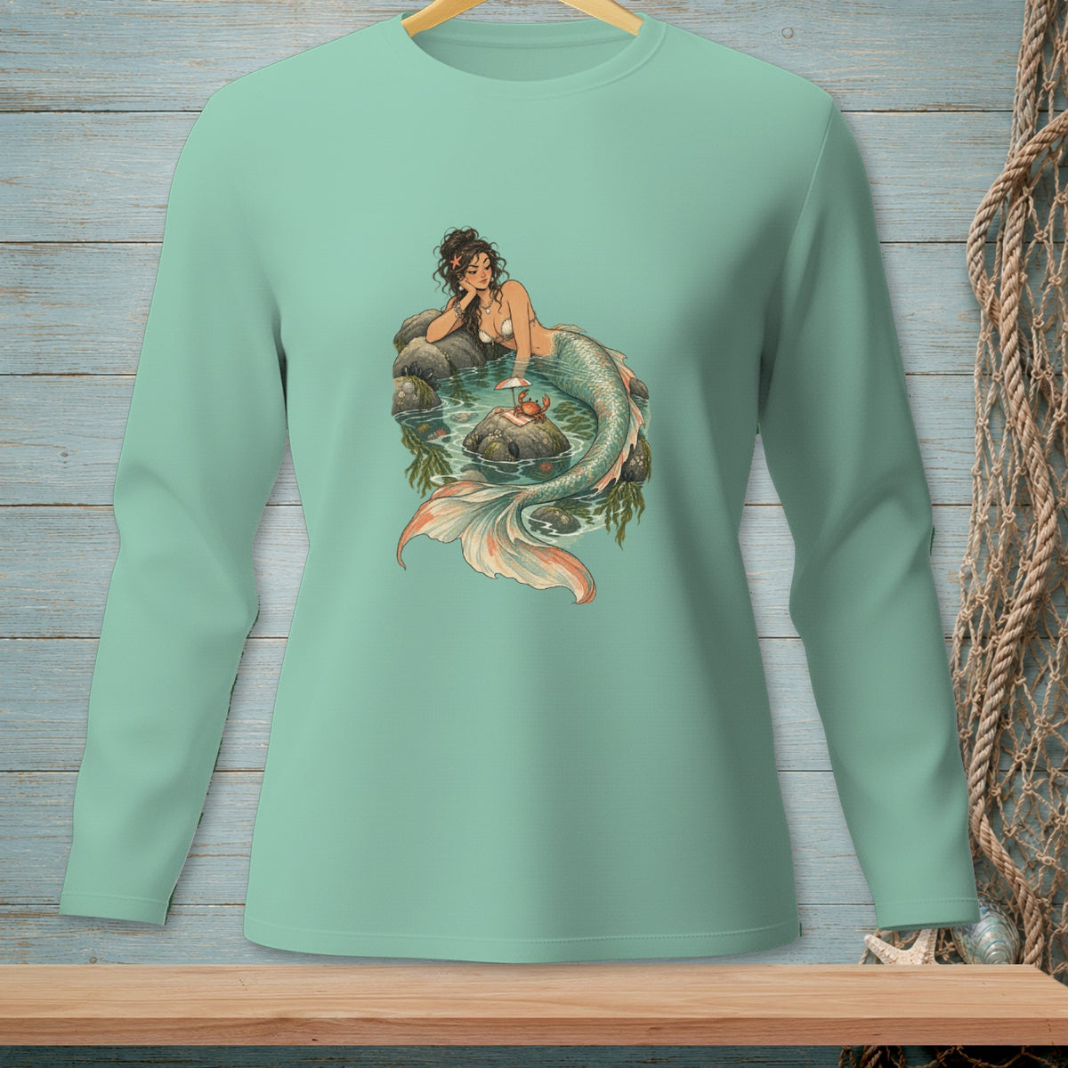 Mermaid resting on rocks in water with a crab on a small island.
