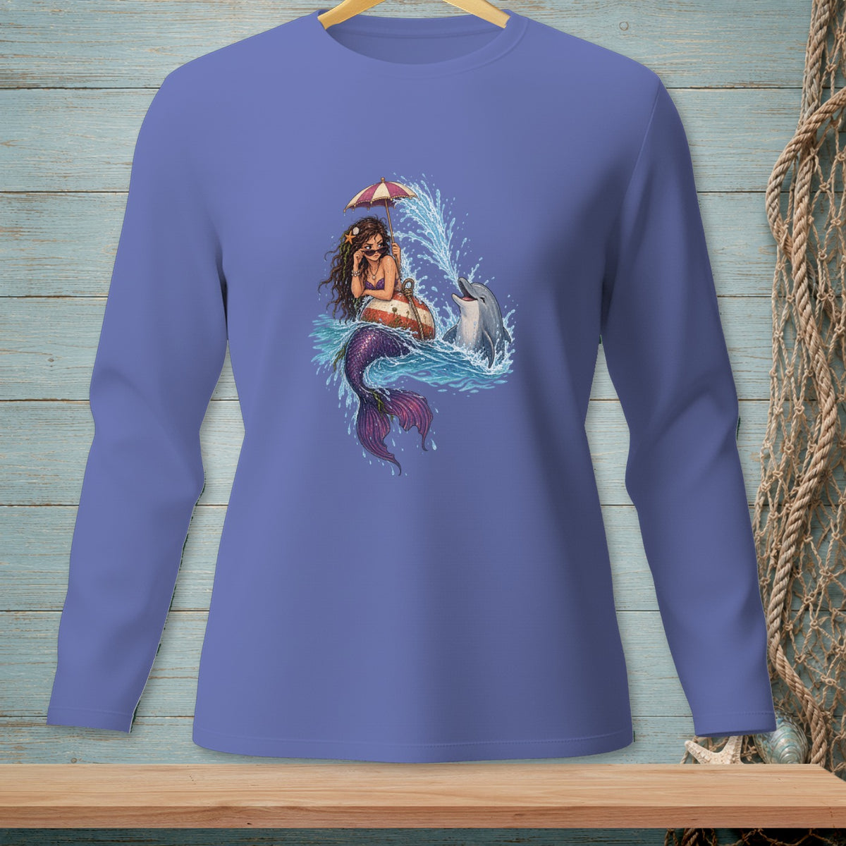 Mermaid holding umbrella with dolphin in splashing water on a purple long sleeve shirt.