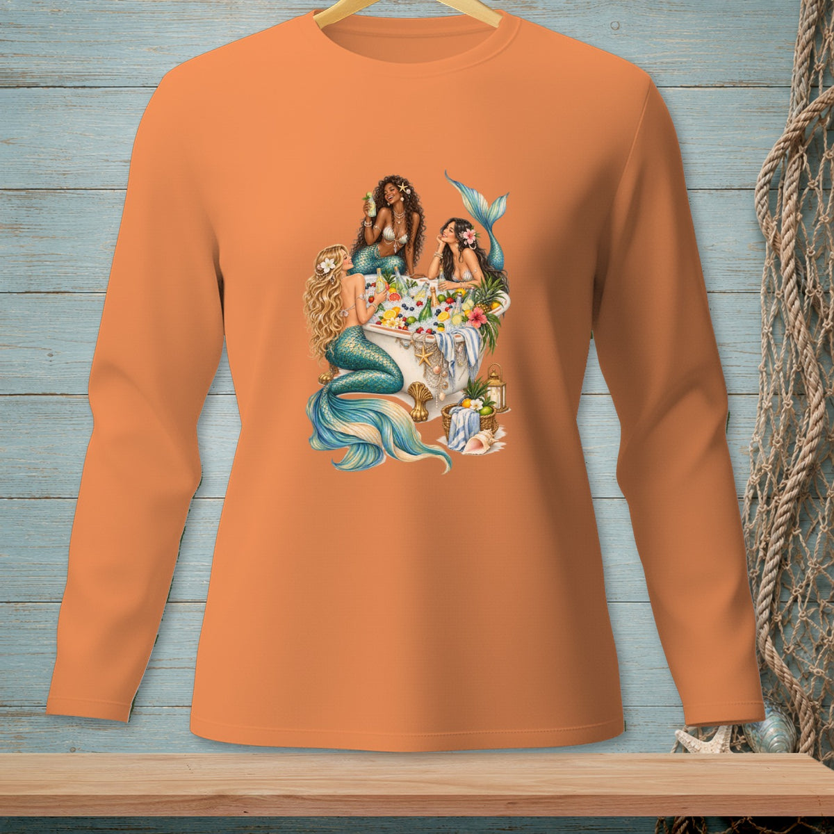 Orange long-sleeve shirt with three mermaids enjoying a bath with fruit and drinks.