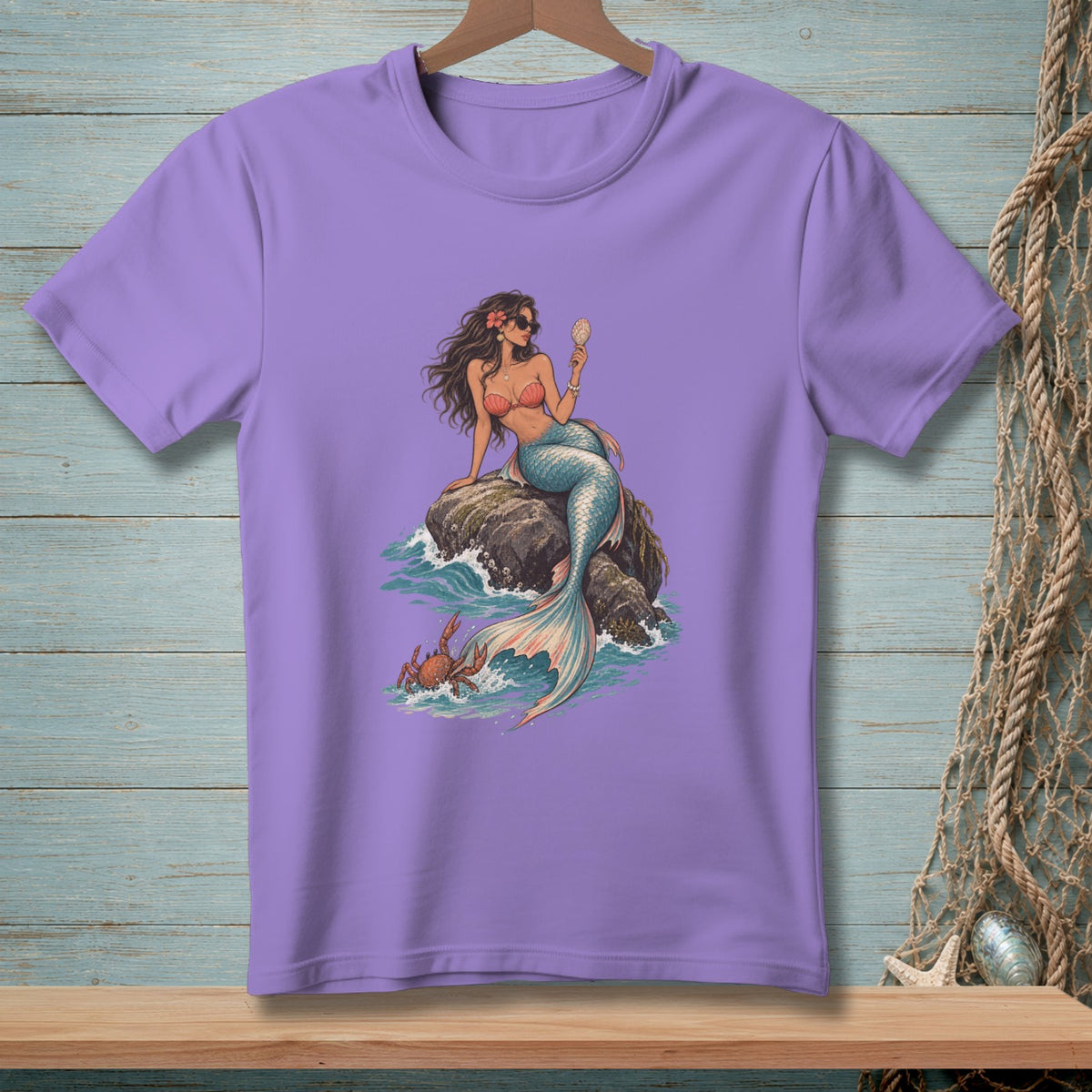 Purple t-shirt with a mermaid sitting on a rock, holding a shell.