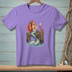 Purple t-shirt with a mermaid and crab on a wooden dock.