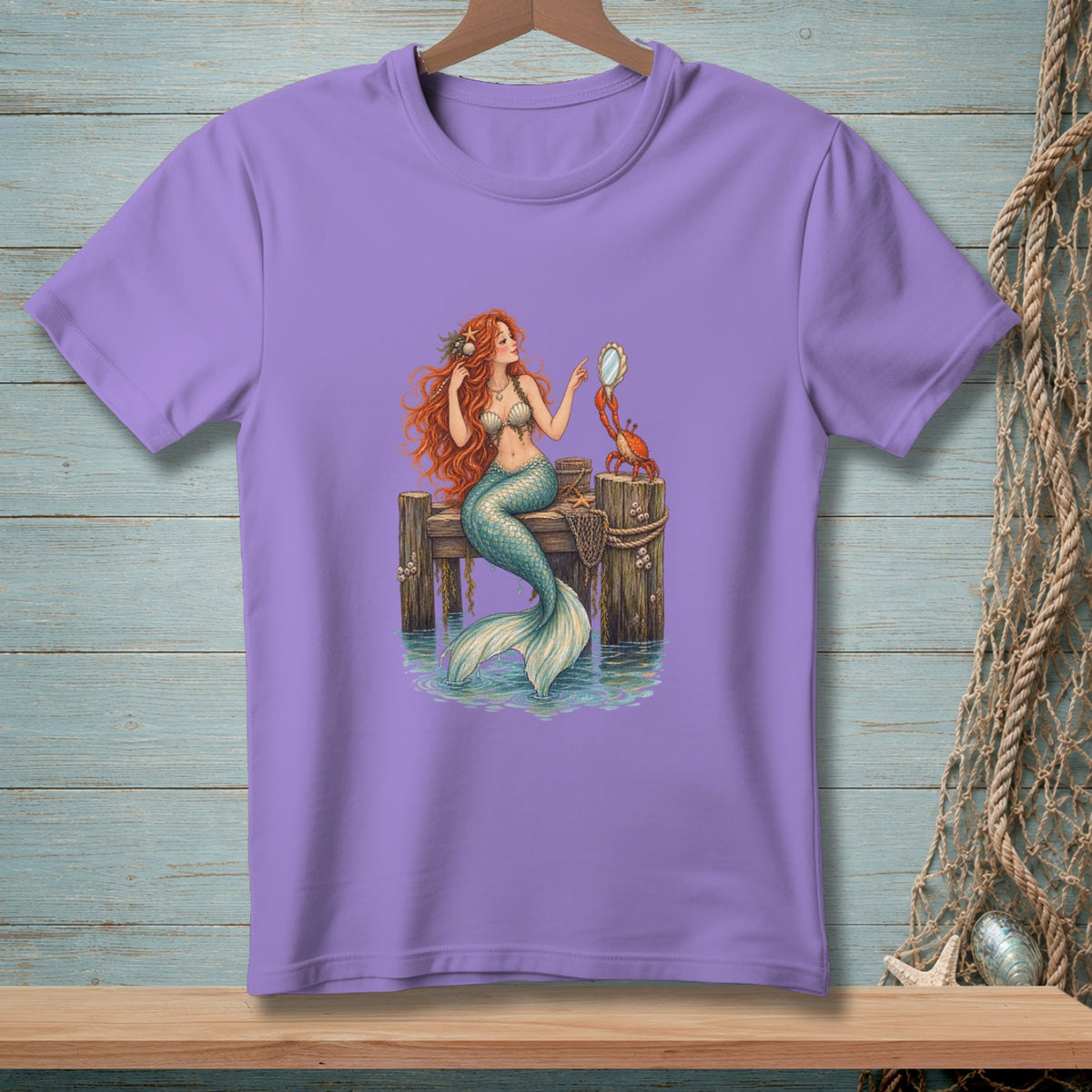 Purple t-shirt with a mermaid and crab on a wooden dock.