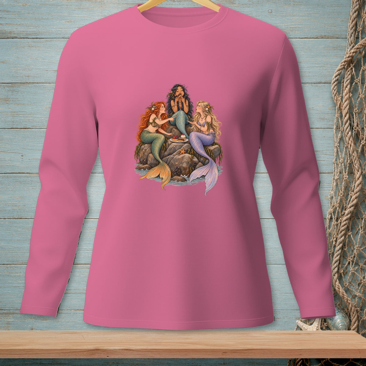 Three mermaids sitting on rocks with a plate of treats.