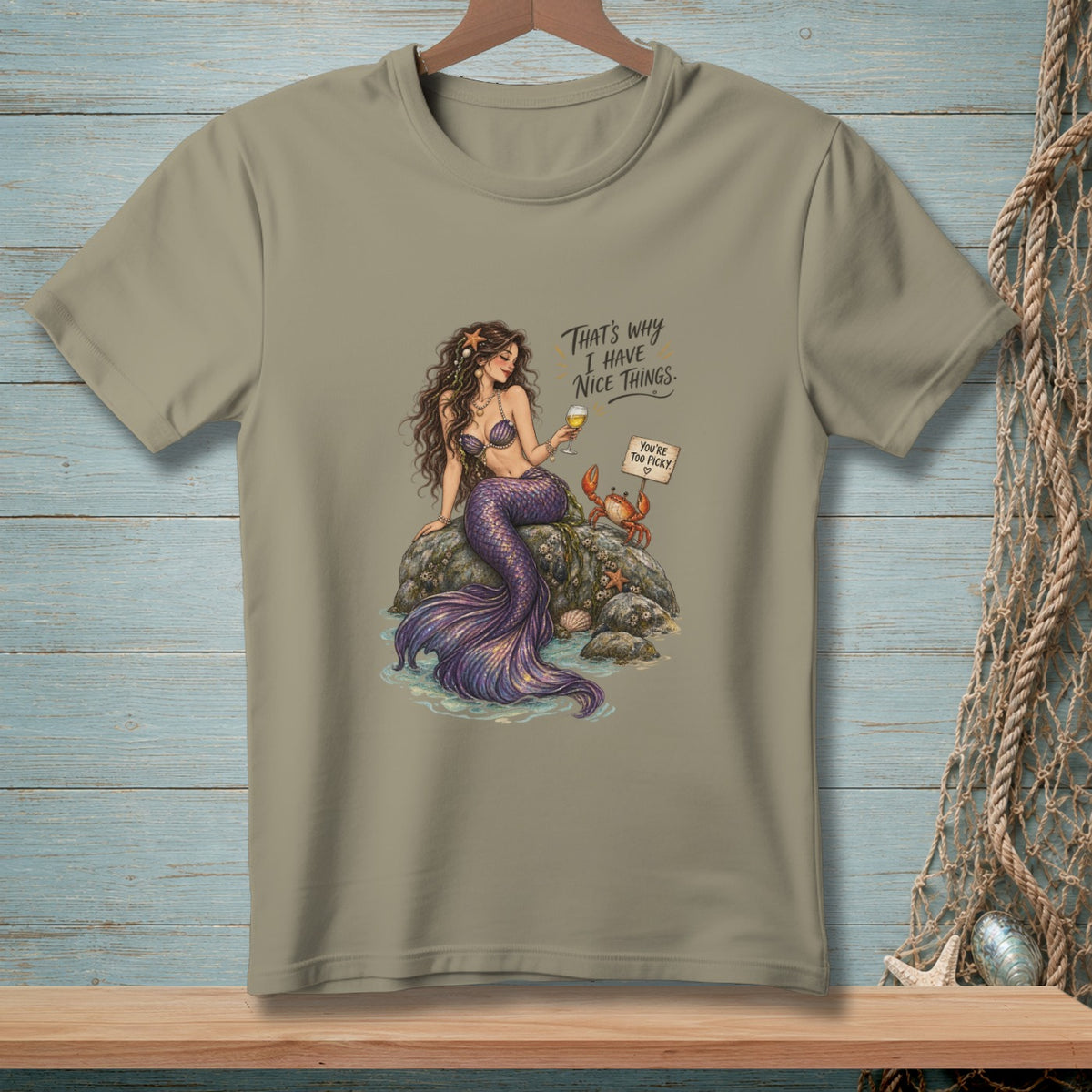Mermaid with purple tail and drink sits on rock with crab, text "That's why I have nice things."