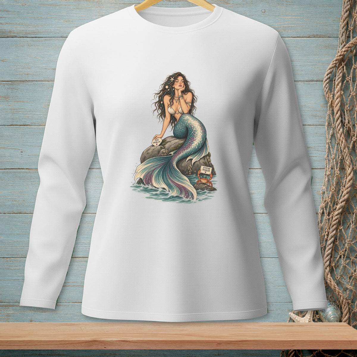 Long-sleeve white shirt with a mermaid graphic sitting on a rock.