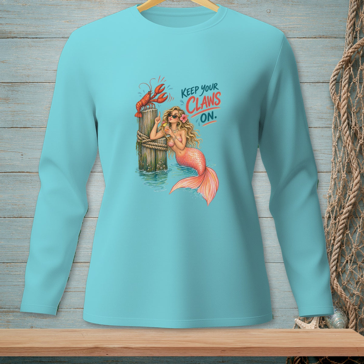 Mermaid and lobster graphic on a teal long-sleeve shirt reading "Keep Your Claws On."