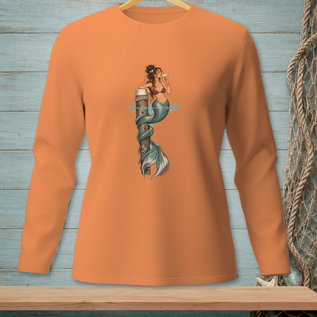 Orange long-sleeve shirt with a graphic of a mermaid on a wooden post drinking a cocktail.