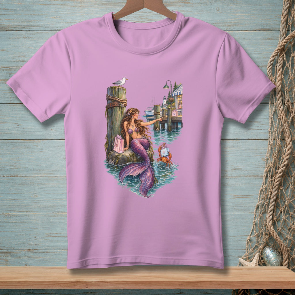 Mermaid with purple tail sits by docks with a crab and gift bag.