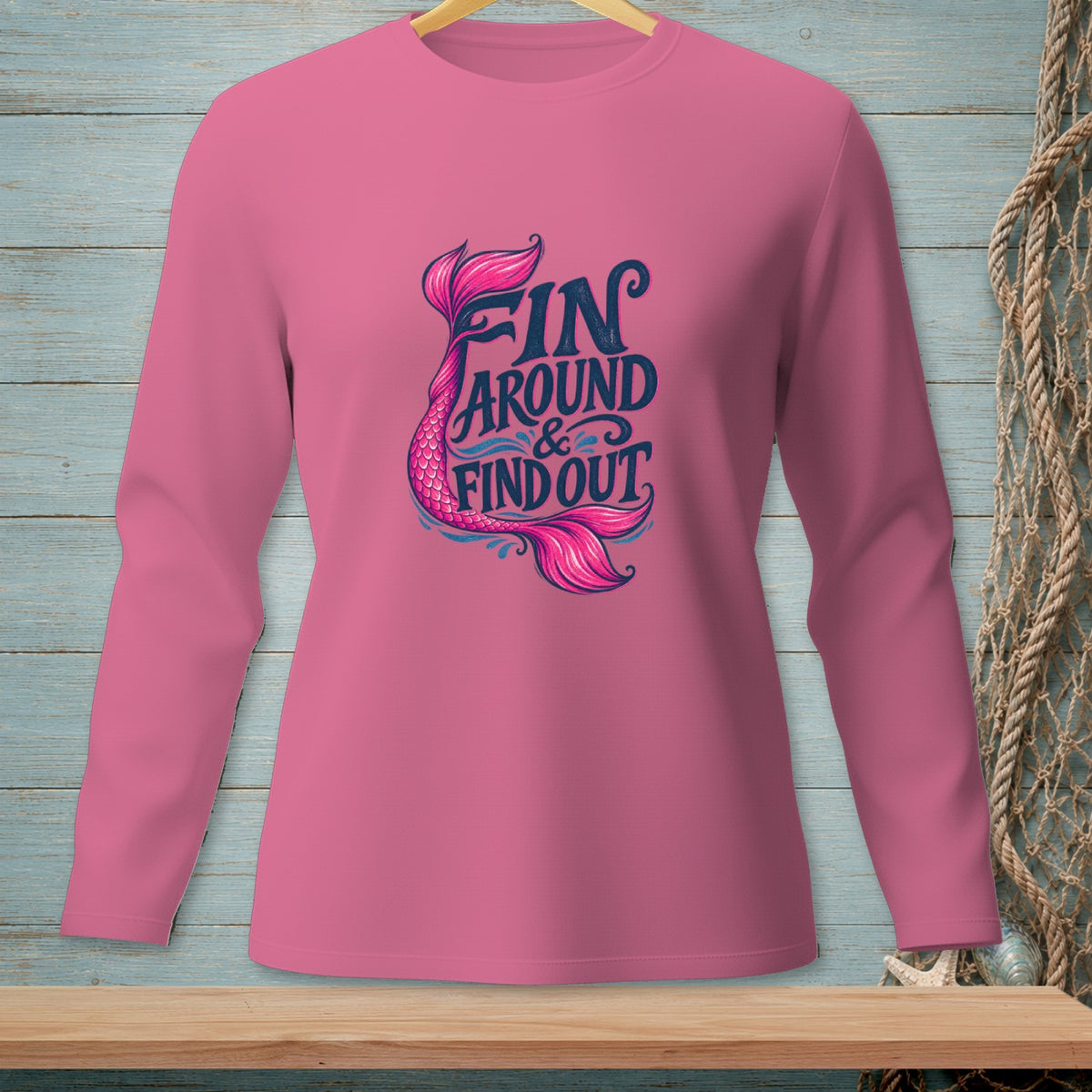 Pink long-sleeved shirt with "FIN AROUND & FIND OUT" and mermaid tail graphic.