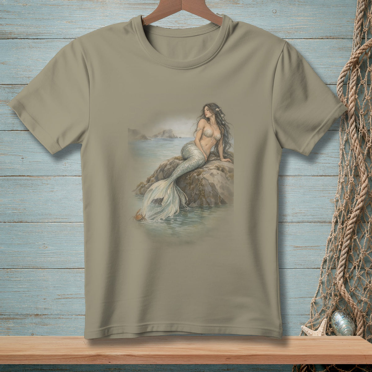 Taupe t-shirt with a watercolor illustration of a mermaid on a rock.