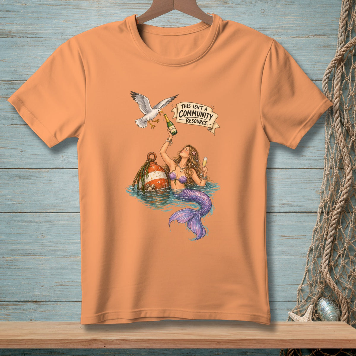 T-shirt graphic: mermaid, seagull, champagne, buoy, and text "This Isn't a Community Resource."