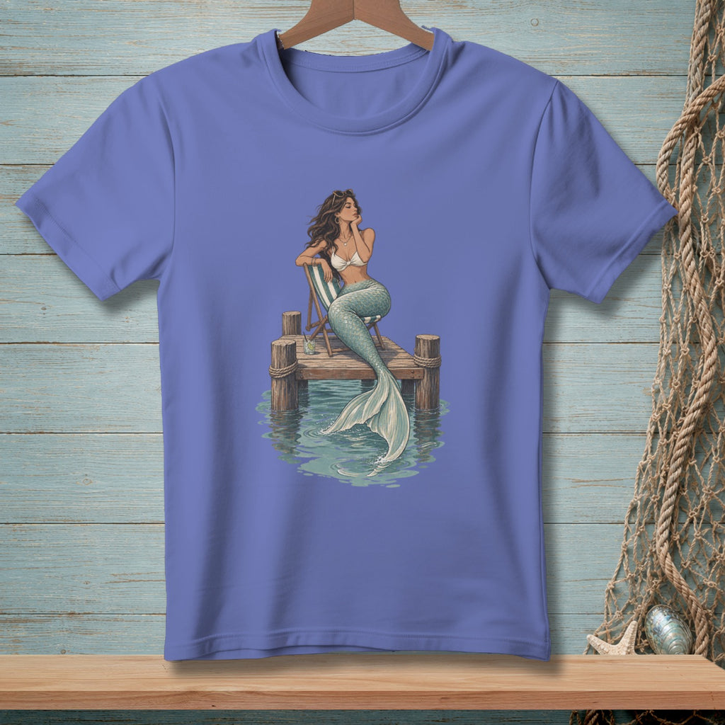 Mermaid sitting on a dock with a striped chair in the water.
